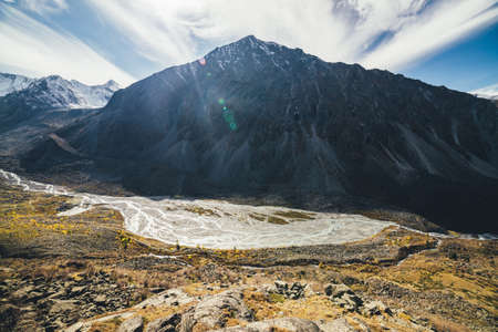 Beautiful alpine landscape with great sharp rocky peak and mountain river with many streams in...
