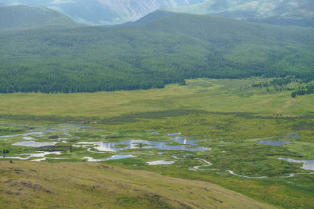 Beautiful green mountain scenery with lake system on tableland. Scenic alpine landscape with lakes group on mountain plateau. Blue lakes system and channels in wide valley. System of mountain lakes.の写真素材
