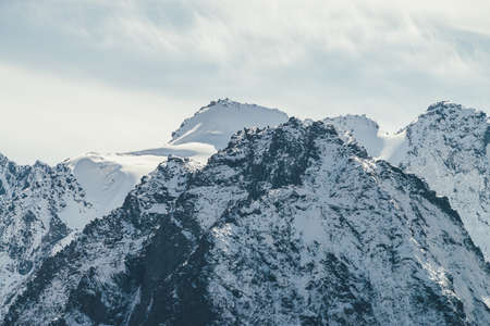 Great view to high snowy mountain wall with peaked top under cirrus clouds in sky. Alpine landscape...