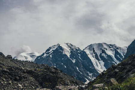 Awesome mountain landscape with great snowy mountain top in cloudy sky. Atmospheric overcast scenery with high mountain and glacier. Big mountains with snow. Beautiful snowy mountains in cloudiness.の写真素材