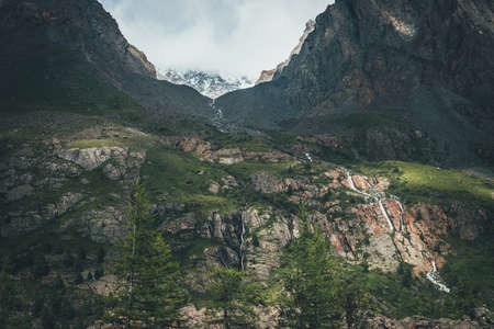 Atmospheric landscape with mountain streams and waterfall of narrow valley among high rocky mountains. Trees on background of beautiful valley with mountain creek. Awesome glen among sharp rocks.の写真素材