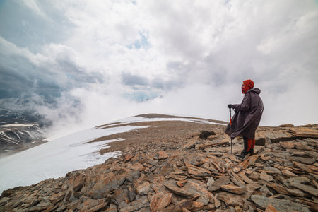 Awesome minimalist mountain landscape with hiker at very high altitude in dense low clouds....