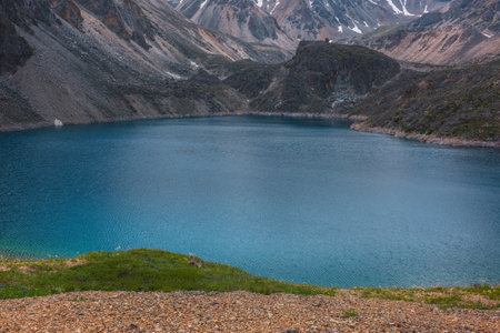Atmospheric landscape with ripples on water surface of deep mountain lake of phantom blue color among sharp rocks and high mountains. Wonderful dramatic view to deep blue mountain lake and rocky cliffの写真素材
