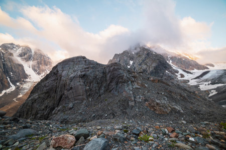 Scenic mountain landscape with sharp rocks in low clouds in golden sunrise colors. Awesome view to rocky mountain top in low clouds with golden dawn colors. Gold morning sunlight on high mountains.の写真素材