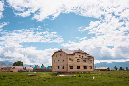 Beautiful wooden house under construction in mountain village in sunlight under cloudy sky. Not completed country house in mountains at changeable weather. Russia, Altai Republic, Kurai, 13 July, 2021のeditorial素材