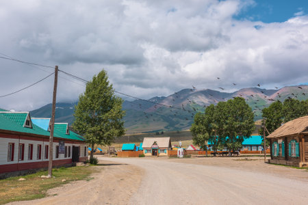 Dramatic landscape inside beautiful mountain village against large mountains at changeable weather. Monument to soldiers of Great Patriotic War in Kurai village. Russia, Altai Republic, 13 July, 2021.のeditorial素材