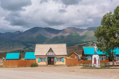 Dramatic landscape inside beautiful mountain village against large mountains at changeable weather. Monument to soldiers of Great Patriotic War in Kurai village. Russia, Altai Republic, 13 July, 2021.のeditorial素材