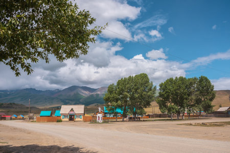 Dramatic landscape inside beautiful mountain village against large mountains at changeable weather. Monument to soldiers of Great Patriotic War in Kurai village. Russia, Altai Republic, 13 July, 2021.のeditorial素材