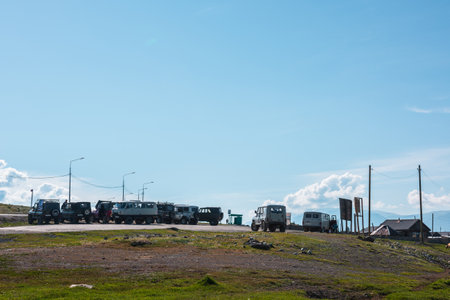Lots of russian off-road vehicles parked by road near Kurai mountain village at sunny day. Group of off-road cars on parked in sunlight under blue sky. Russia, Altai Republic, Kurai, 01 July, 2021.のeditorial素材