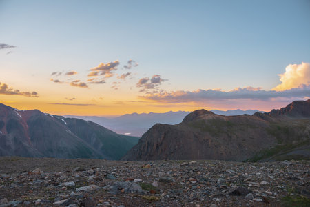 Atmospheric alpine landscape with large mountains in orange dawn sky. Colorful top view to high mountain range under cloudy sky in sunset colors. Awesome mountain sunset scenery at very high altitude.の写真素材