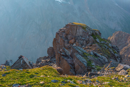 Awesome mountain landscape with cliff above abyss. Beautiful scenery with green grass near sharp rock near precipice edge. Scenic sunny view to green cliff with sharp stones at very high altitude.の写真素材