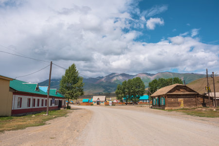 Dramatic landscape inside beautiful mountain village against large mountains at changeable weather. Monument to soldiers of Great Patriotic War in Kurai village. Russia, Altai Republic, 13 July, 2021.のeditorial素材