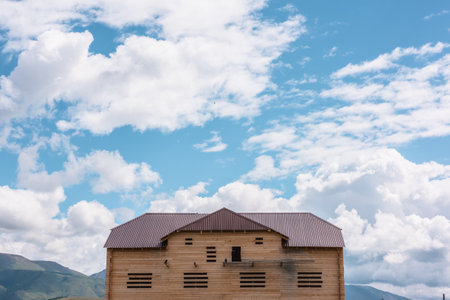 Beautiful wooden house under construction in mountain village in sunlight under cloudy sky. Not completed country house in mountains at changeable weather. Russia, Altai Republic, Kurai, 13 July, 2021のeditorial素材
