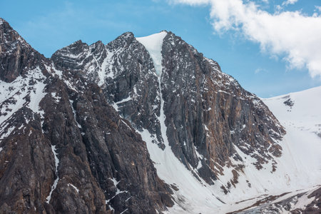 Scenic alpine landscape with snowy mountain peak in sunny day. Awesome landscape with rocky pinnacle with snow in sunlight. Beautiful view to snow mountain top and sharp rocks at very high altitude.の写真素材