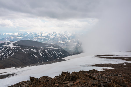 Awesome top view through clouds to high snowy mountains. Scenic landscape with beautiful snow...