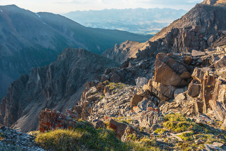 Vastness sunny mountain view from cliff at very high altitude. Scenic alpine landscape with beautiful sharp rocks and couloirs in sunlight. Beautiful mountain scenery on abyss edge with sharp stones.の写真素材
