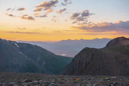 Atmospheric alpine landscape with large mountains in orange dawn sky. Colorful top view to high mountain range under cloudy sky in sunset colors. Awesome mountain sunset scenery at very high altitude.の写真素材