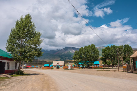 Dramatic landscape inside beautiful mountain village against large mountains at changeable weather. Monument to soldiers of Great Patriotic War in Kurai village. Russia, Altai Republic, 13 July, 2021.のeditorial素材