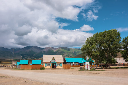 Dramatic landscape inside beautiful mountain village against large mountains at changeable weather. Monument to soldiers of Great Patriotic War in Kurai village. Russia, Altai Republic, 13 July, 2021.のeditorial素材