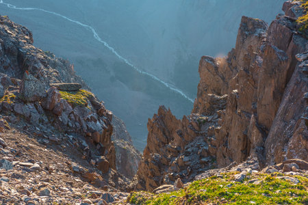 Awesome mountain view from cliff at very high altitude. Scenic landscape with beautiful sharp rocks near precipice and couloirs in sunlight. Beautiful mountain scenery on abyss edge with sharp stones.の写真素材
