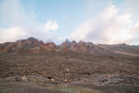 Scenic alpine landscape with rocky mountains in dense low clouds in morning sunlight. Colorful mountain scenery with sharp rocks among thick low clouds. Awesome view to high rockies in low cloudiness.の写真素材