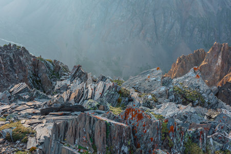 Awesome mountain view from cliff at very high altitude. Scenic alpine landscape with edge of precipice with sharp rocks against large mountain wall. Beautiful scenery on abyss edge with sharp stones.の写真素材