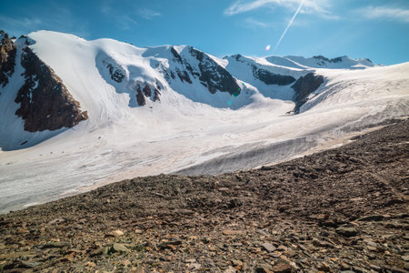 Scenic mountain landscape with large glacier in sunlight. Awesome scenery with glacial tongue under sun in blue sky. Beautiful alpine view to snow mountain tops at very high altitude in sunny day.の写真素材