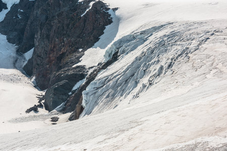 Scenic mountain landscape with icefall on large glacier near rocks. Awesome alpine scenery with glacial tongue in sunlight. Atmospheric view to beautiful glacier tongue texture at very high altitude.の写真素材