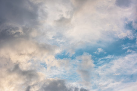 Scenic view to clouds illuminated by sunset in blue sky. Nature background of cloudy sky in sunrise. Beautiful landscape with sunset lit clouds in evening sky. Nature texture of sunset cloudy skies.の写真素材