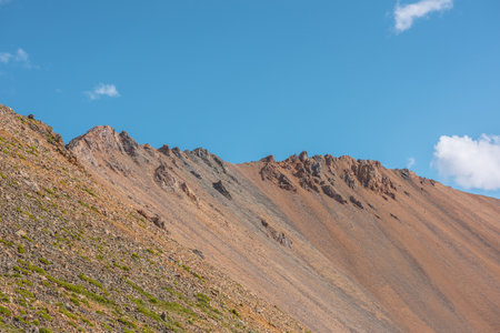Scenic landscape with sunlit high rocky mountain ridge under blue sky in sunny day. Colorful scenery with large mountain wall in sunlight. Scenic view to sharp rocks on mountain top in bright sun.の写真素材