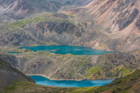 Scenic view to beautiful group of blue mountain lakes at various heights among rocks and hills in bright sun. Two long parallel blue lakes at different highs among sunlit green hills and mountains.の写真素材