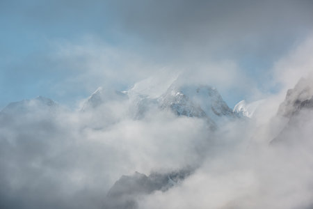 Beautiful scenery with high snowy mountains in thick clouds. Scenic view to large snow mountain in clearance of dense fog.の写真素材