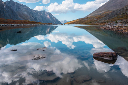 Tranquil autumn landscape with clouds reflection on smooth mirror surface of mountain lake in high...