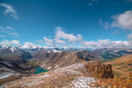Two high mountain valleys separated by sharp rocky ridge. Freshly fallen snow on stony pass in...