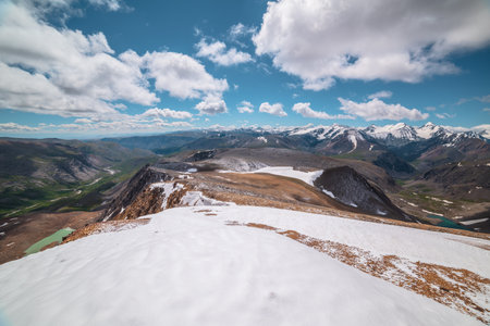 Scenic panoramic top view along large wide mountain range with snowfield and freshly fallen snow in...
