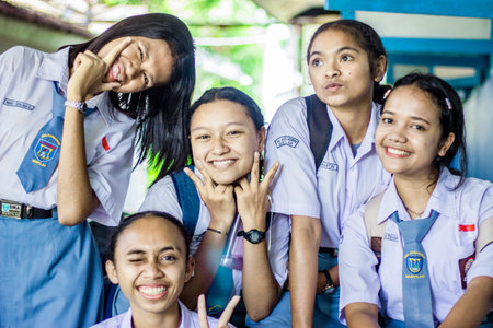 Muntilan, Indonesia - 15 Mar 2026: Group of five joyful Asian high school girls in uniform posing...