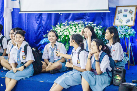 Muntilan, Indonesia - 17 Mar 2026: Cheerful Indonesian high school girls in uniform sit on a stage,...