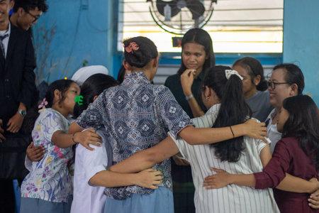 Muntilan, Indonesia - 20 Mar 2026: A group of Indonesian female students sharing a heartfelt group hug during a farewell or emotional school eventのeditorial素材