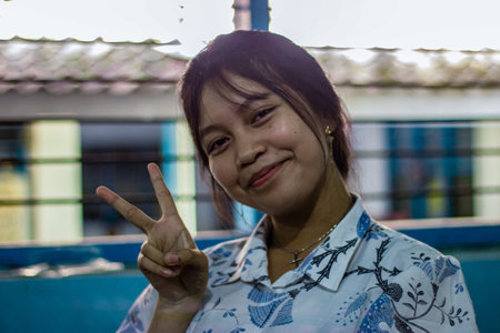 Muntilan, Indonesia - 26 Mar 2026: Portrait of a smiling Southeast Asian girl in batik shirt making...