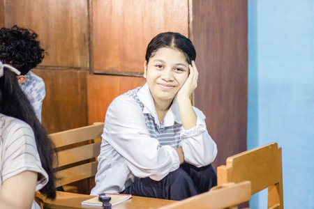 Muntilan, Indonesia - 30 Mar 2026: Young Asian female student smiling while sitting at a desk in a...