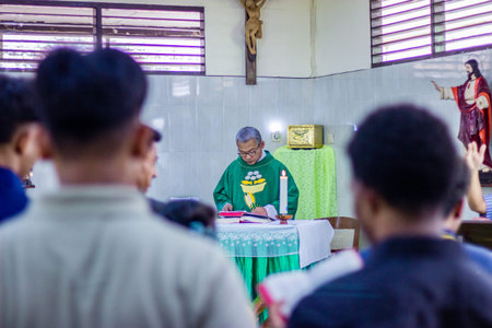 Muntilan, Indonesia - 3 Apr 2026: Catholic priest in green vestments reading at the altar during...