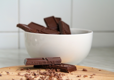 broken chocolate on a wooden base and a white bowl