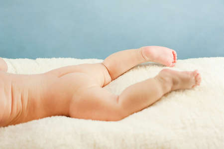Naked butt of a baby with powdered irritation and prysy at the doctor's appointment on an isolated blue background. Concept of child healthの写真素材