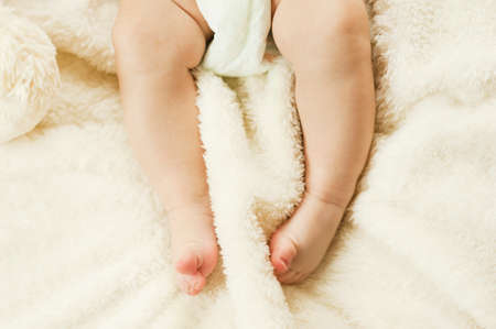 small gentle healthy legs of a newborn baby gnawing on a plaid. Healthy children conceptの写真素材