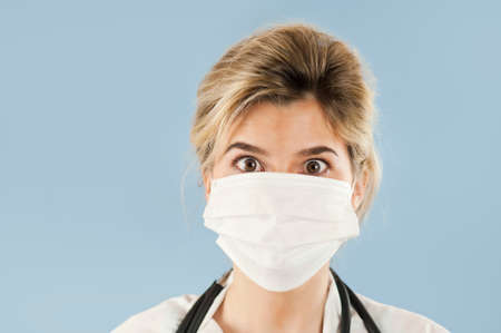 Close-up portrait of a beautiful girl doctor on a blue isolated background. Concept medicine and healthの写真素材