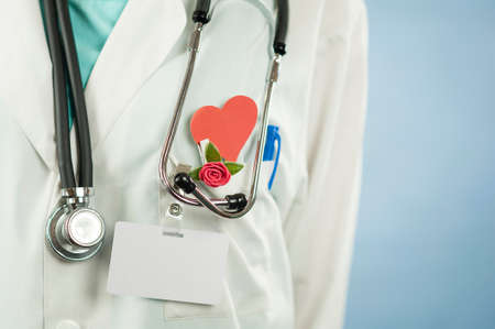Young beautiful girl doctor with a red heart in her hands on a blue isolated background.Concept of loveの写真素材