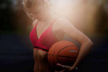 Portrait of a athletic woman outdoors posing while listening to music with headphones holding a basketballの写真素材