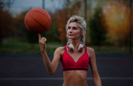 Beautiful sexy sports girl twists on one finger the ball looking at cameraの写真素材