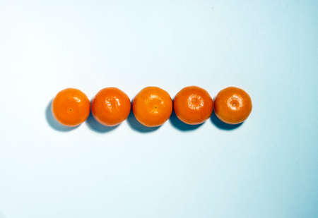 Mandarin whole and halves in lines with hard shadows on blue background, flat lay image.の写真素材