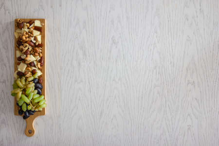 Cheeseboard overhead view, cheese assortment served grapes nuts and olives, healthy food concept